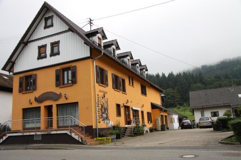 Ein zweistöckiges Gebäude mit gelber Fassade, einer Treppe, die zum Eingang führt, und einem Schild, das es als Restaurant kennzeichnet.