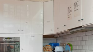 Una cocina con armarios blancos, piso rojo y salpicadero de azulejos.