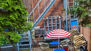 Un tablero de ajedrez dispuesto al aire libre, con un patio de ladrillo y una escalera al fondo.