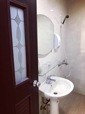 A bathroom with a white sink, a glass shower enclosure, and a mirror above the sink. - Dongyin First Homestay (Dongyin Town)