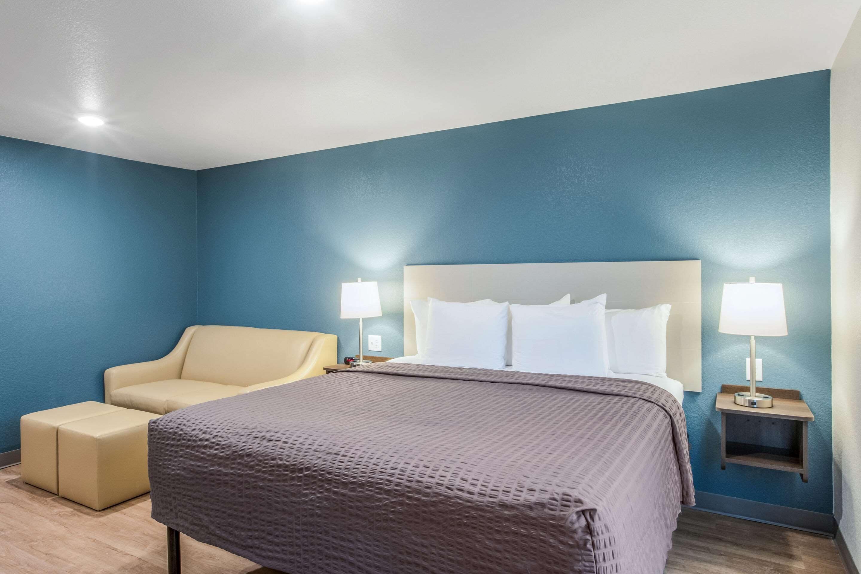 A hotel room with a bed, a chair, and two bedside lamps.