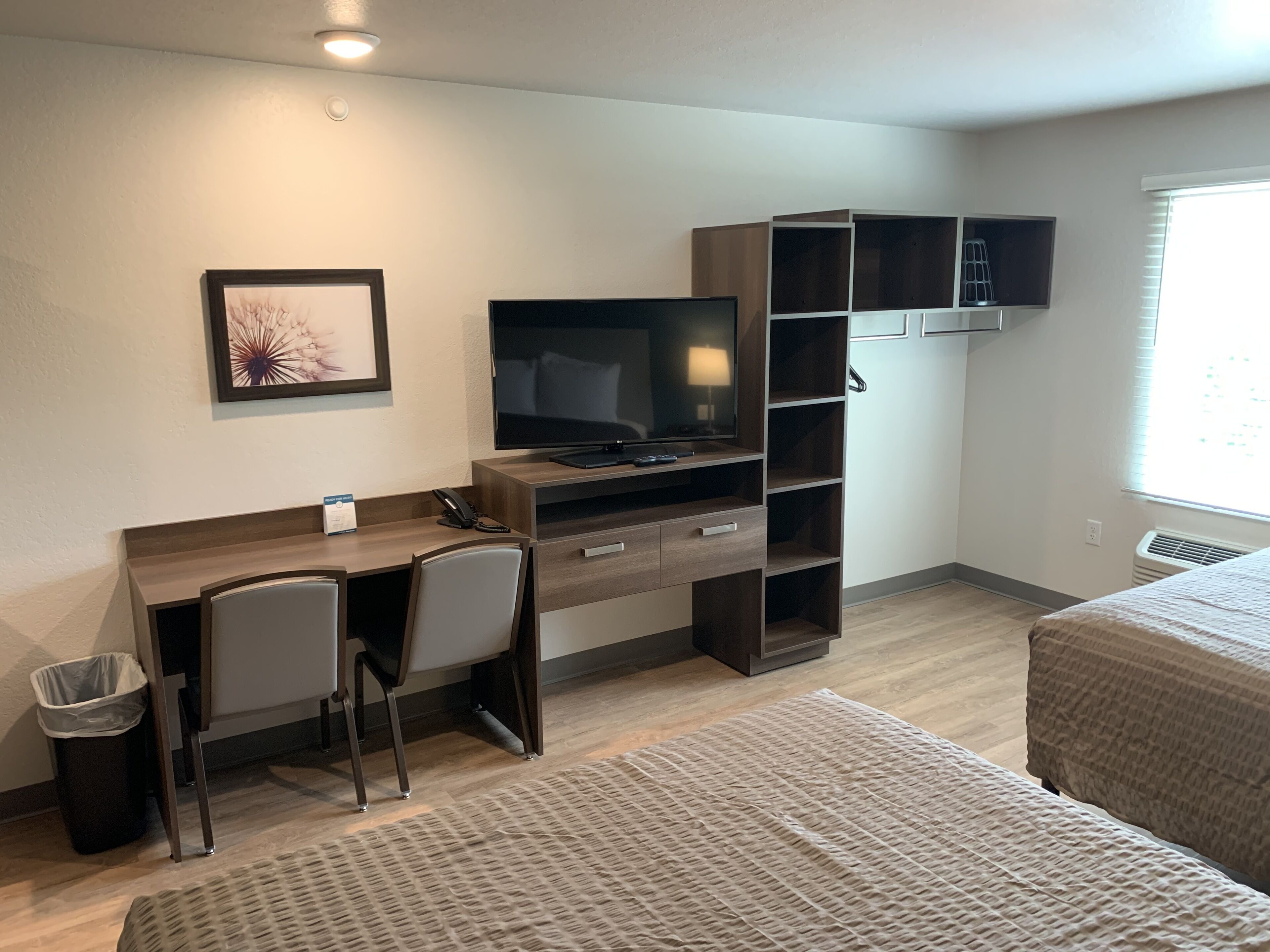 Une chambre à coucher comprenant un lit, un bureau avec une chaise, un téléviseur et des étagères intégrées.