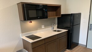 A compact kitchen with a microwave, double sink, and black refrigerator. - WoodSpring Suites Atlanta McDonough (McDonough)