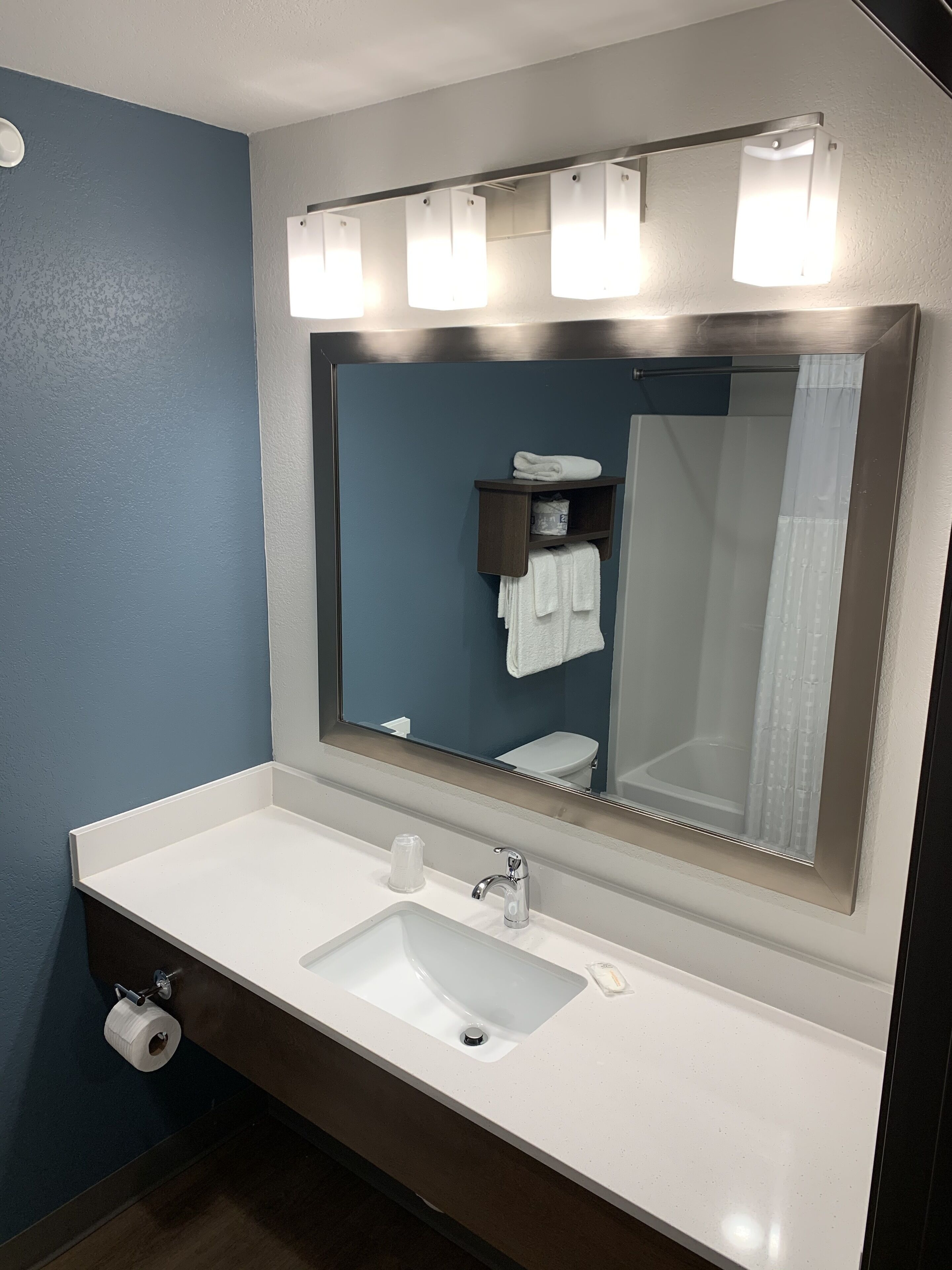 A bathroom with a white sink, a mirror, and a towel rack.