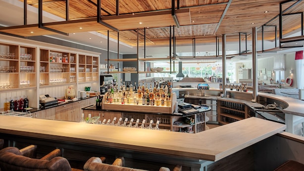 A bar area with a long counter, multiple seating options, and a variety of bottles and glasses. - Ferienwohnungen Blischke (Wittmund)