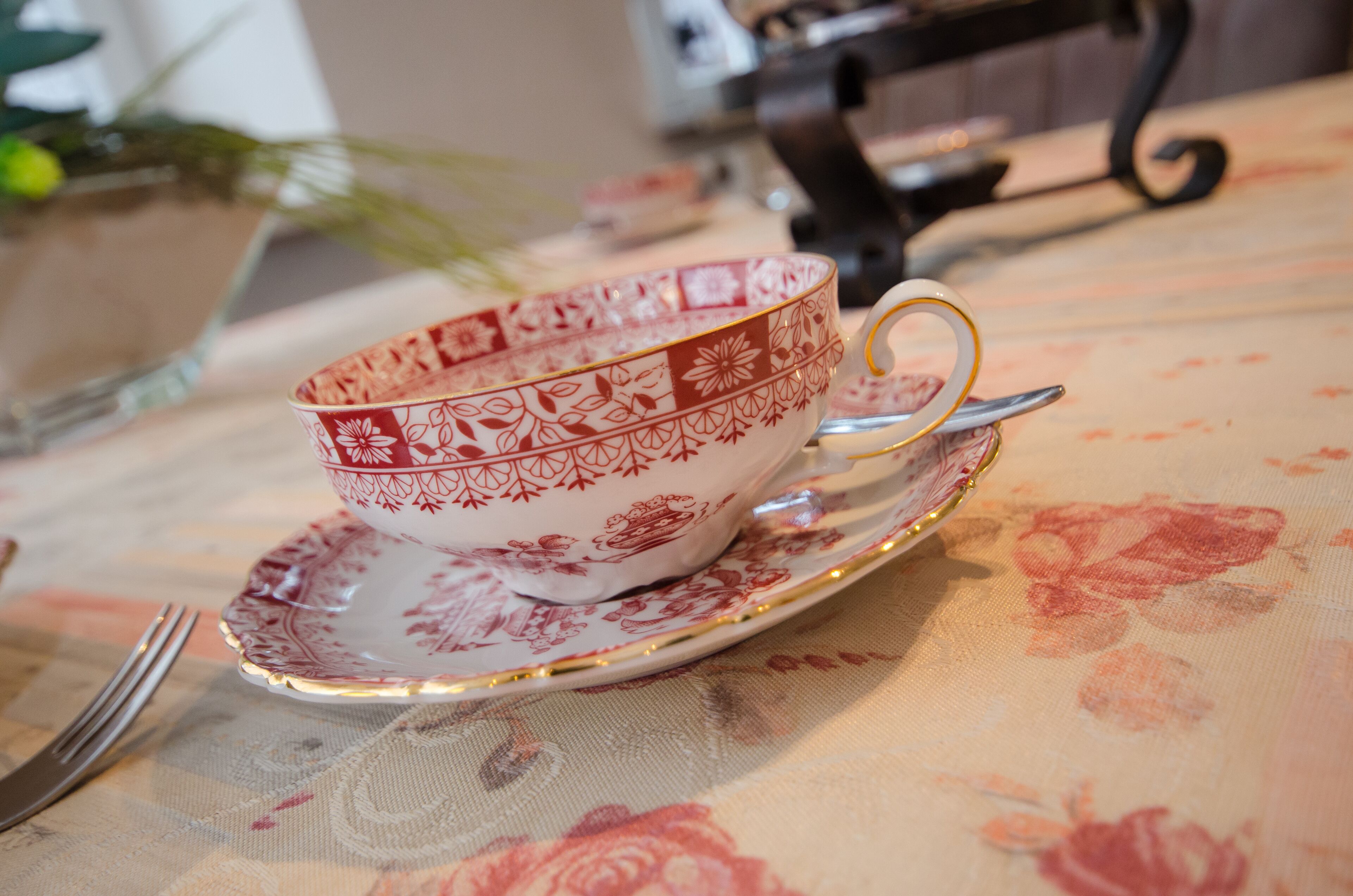 Une table dressée avec une tasse à thé et sa soucoupe, une fourchette et une cuillère.