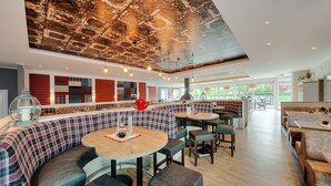 A restaurant with a modern interior, featuring a mix of seating options including booths and tables, a brick ceiling, and a view of the outdoors. - Ferienwohnungen Blischke (Wittmund)