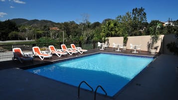 Piscina com espreguiçadeiras e vista para as montanhas.