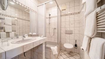 Ein modernes Badezimmer mit einer begehbaren Glasdusche, einer Badewanne, einer Toilette und einem Waschtisch mit Waschbecken und Spiegel.