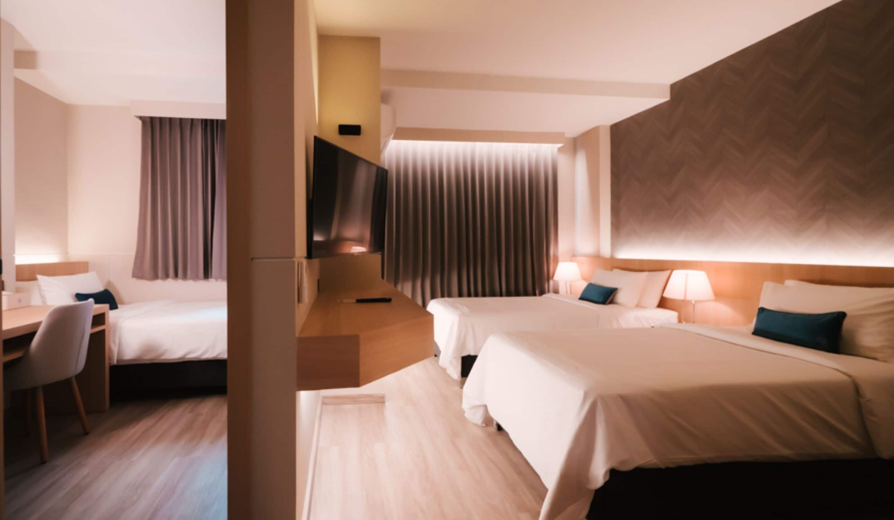 A hotel room with two beds, a desk, and a chair.