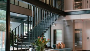 Un interior moderno con escalera, zona de estar y ventilador de techo.