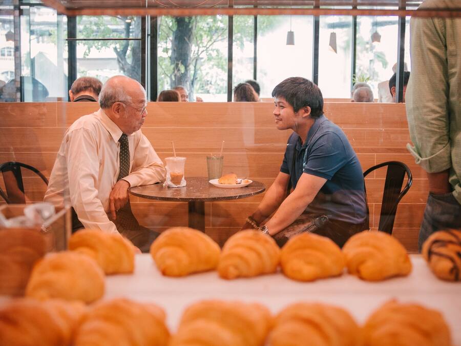 Interior de un restaurante con mesas, sillas y un ventanal grande.