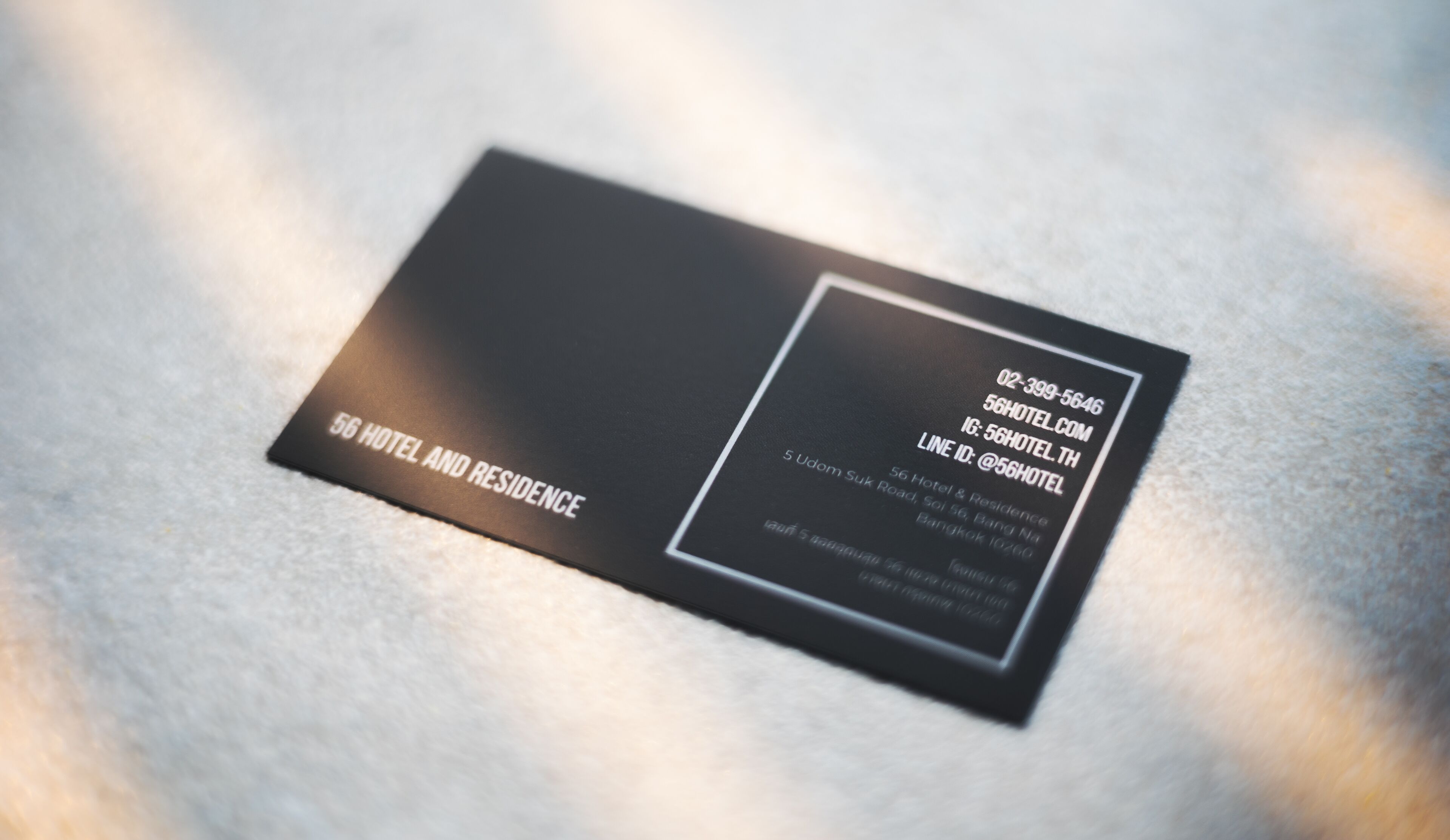 A black business card for 56 Hotel and Residence with contact details and address.