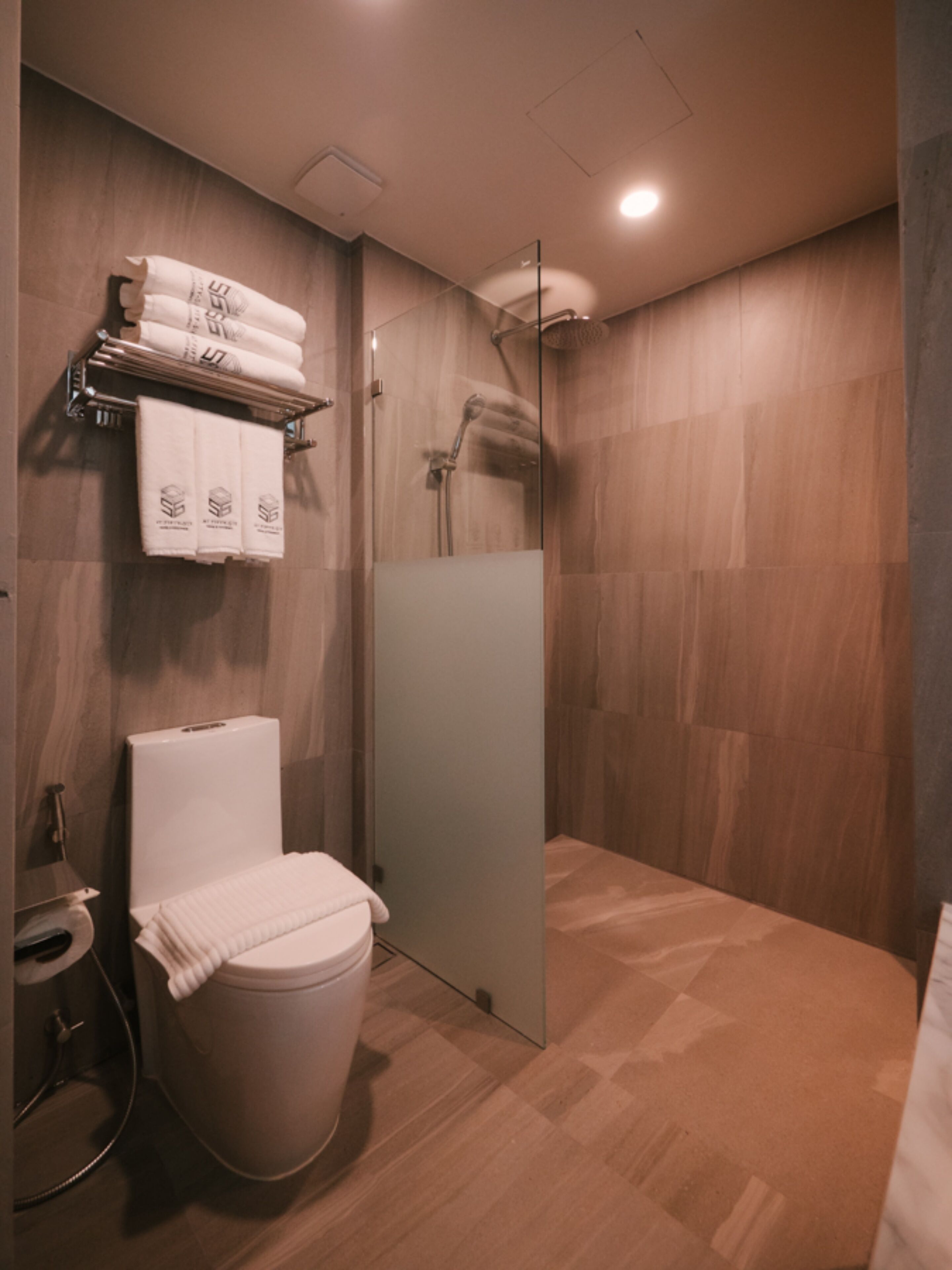 Een moderne badkamer met toilet, douche en handdoekrek.