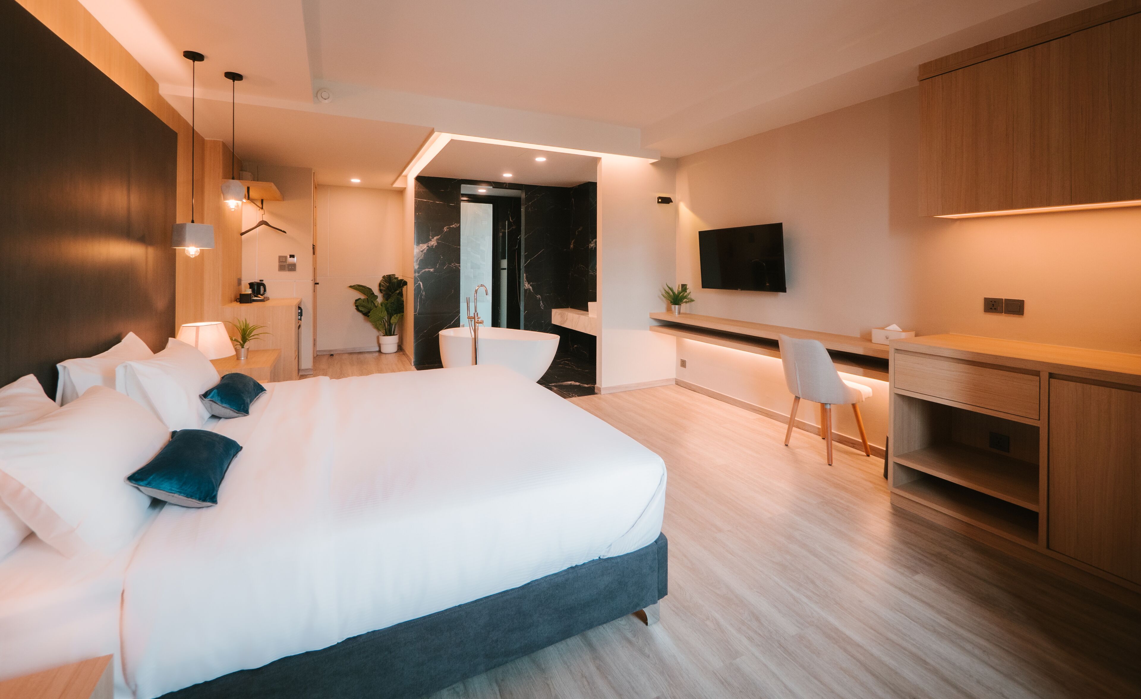 A modern hotel room with a large bed, a desk, a flat-screen TV, and a bathroom with a marble wall.