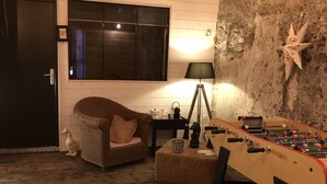 Una habitación acogedora con una mesa de fútbol, una silla de mimbre, una lámpara y una decoración de estrella en la pared.