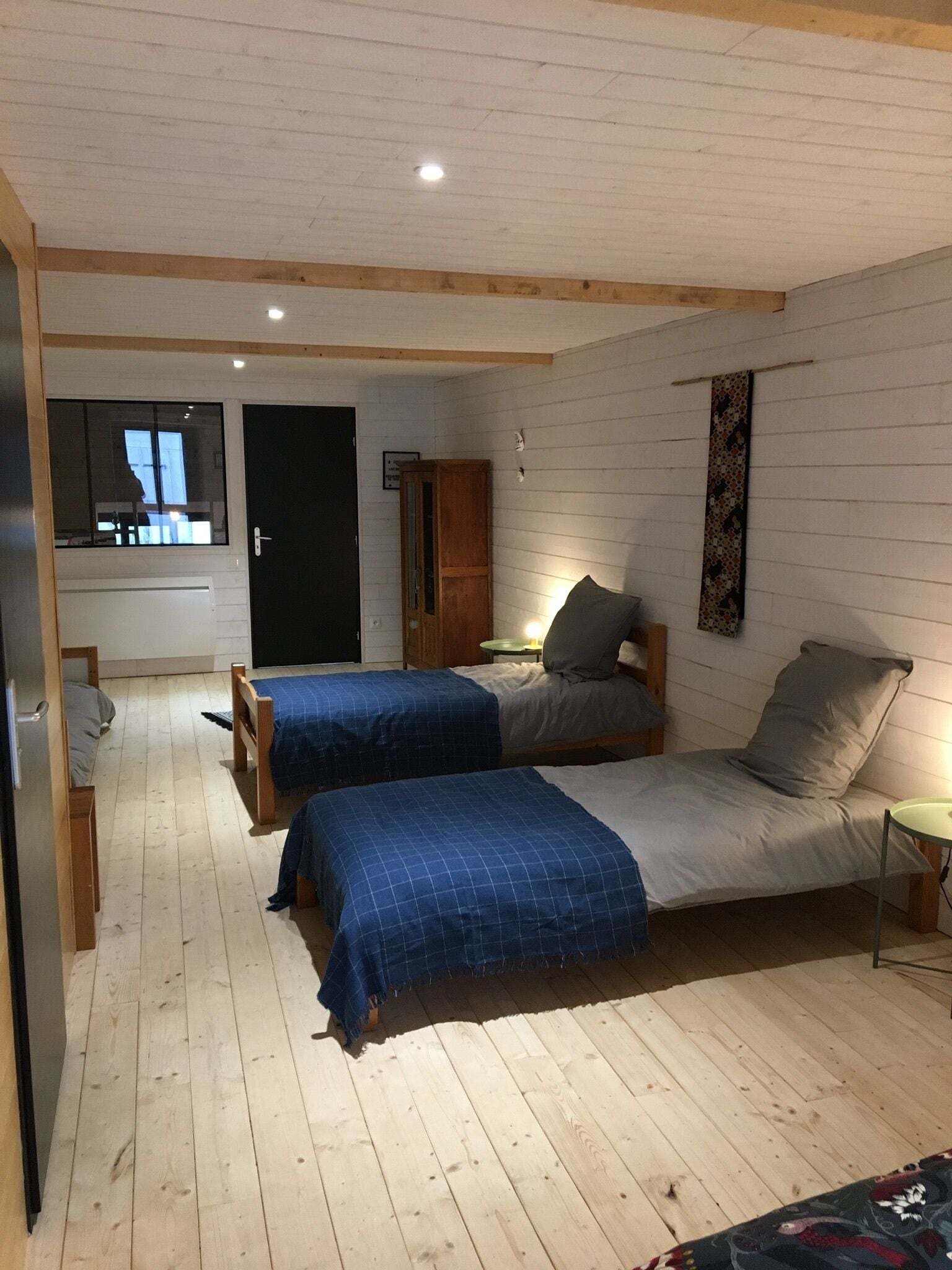 Ett mysigt sovrum med två sängar, en trägarderob och ett litet bord.