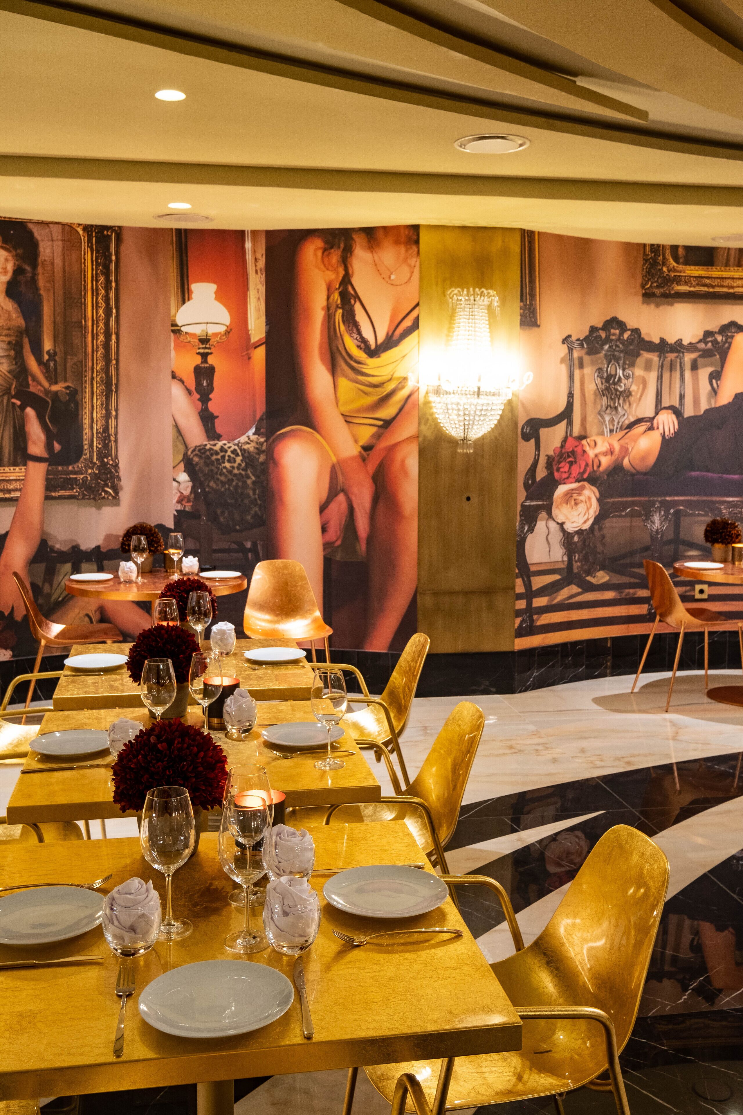 Un comedor con mesas dispuestas para dos, con manteles dorados y sillas modernas.