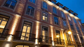 A multi-story building with a brick facade, multiple windows, and balconies with wrought iron railings.