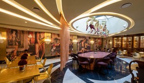 A luxurious dining area with a central round table, surrounded by modern chairs, and a high ceiling with a unique light fixture. - Madalena by The Beautique Hotels (Lisbon)