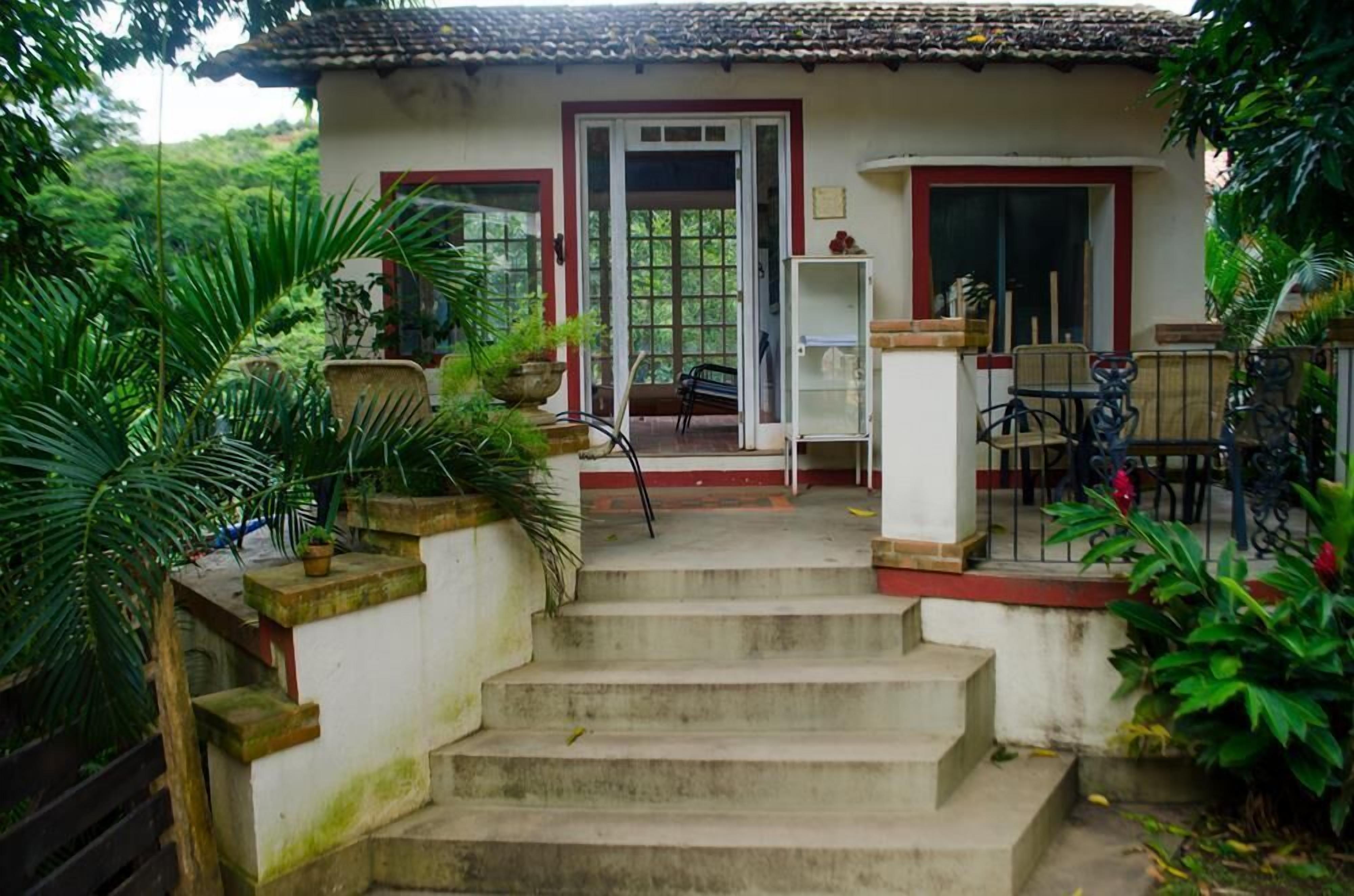 A house with a tiled roof, a staircase leading to a door, and a small outdoor seating area with chairs and a table.