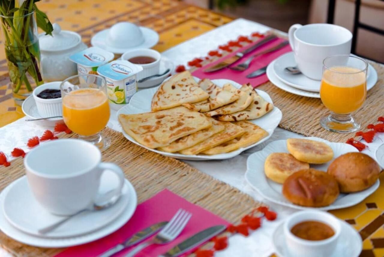 En morgenmadsopstilling med et fad fladbrød, et glas appelsinjuice og diverse tilbehør.