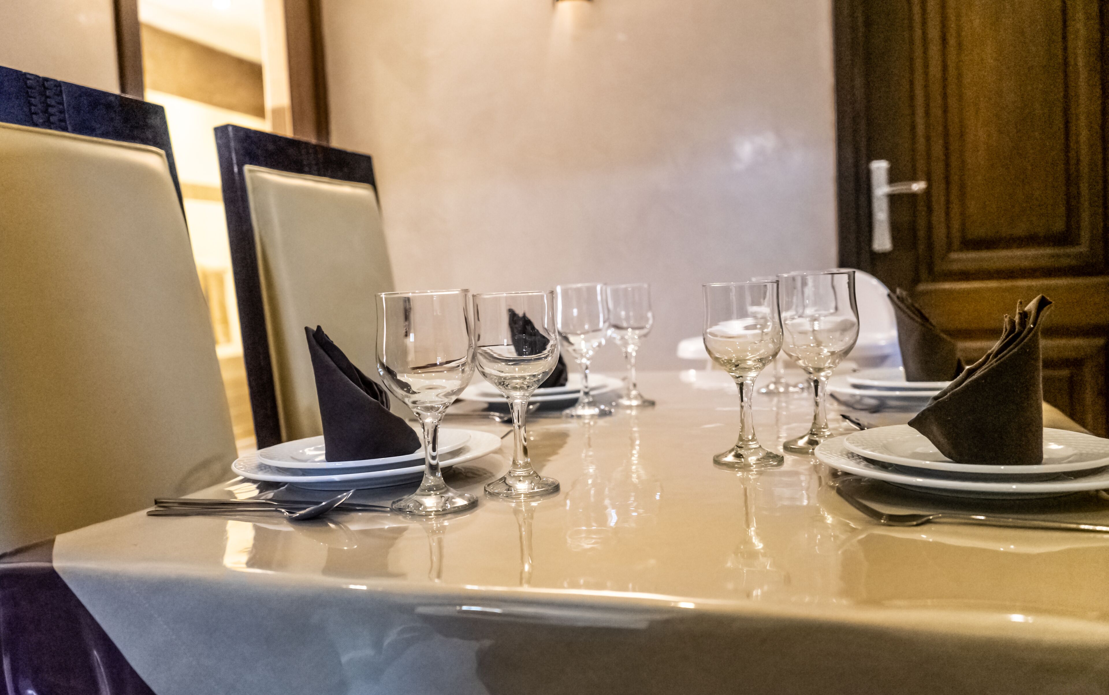 A dining table set with multiple wine glasses, plates, and a folded napkin.