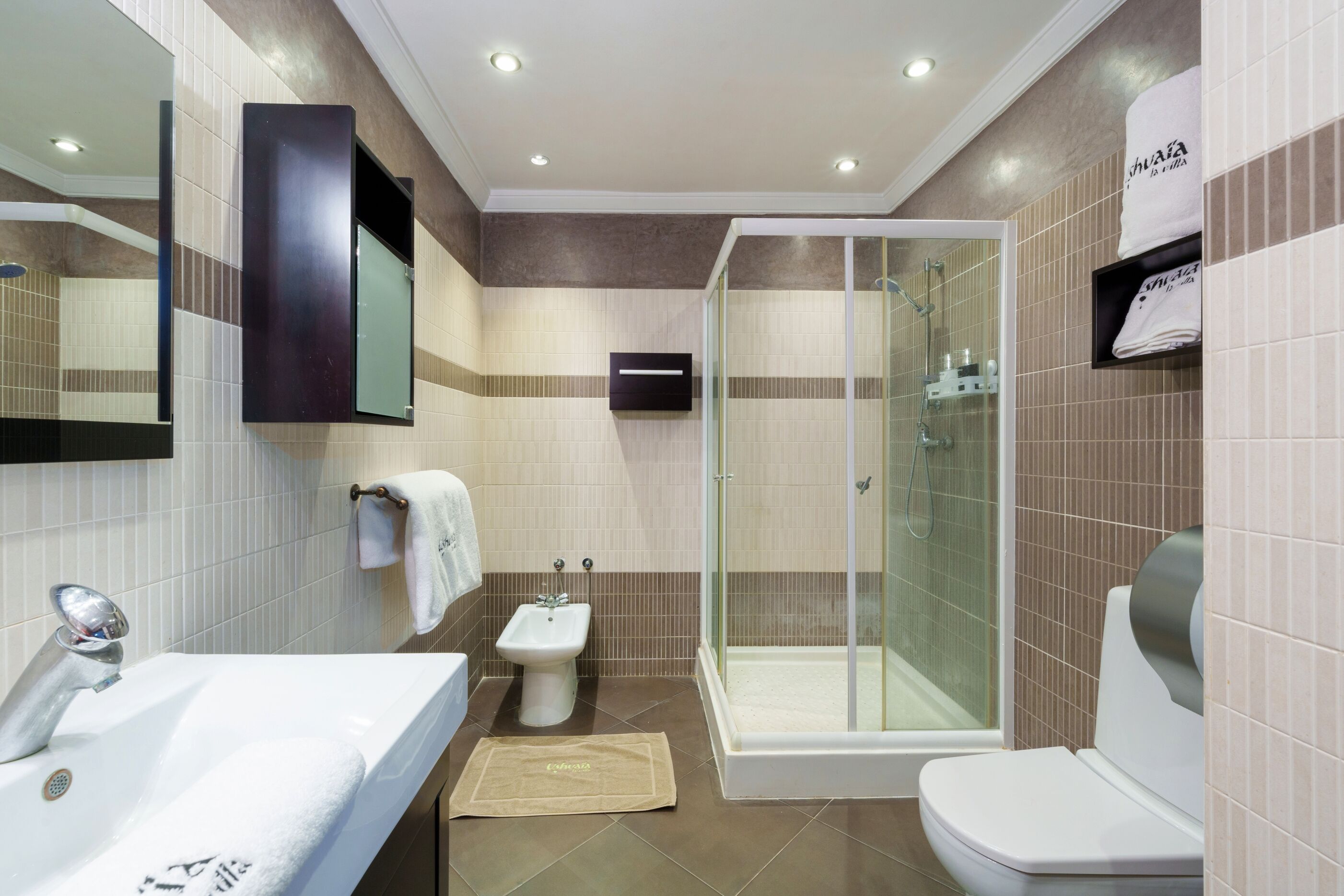 A modern bathroom with a sink, bidet, toilet, and glass-enclosed shower.