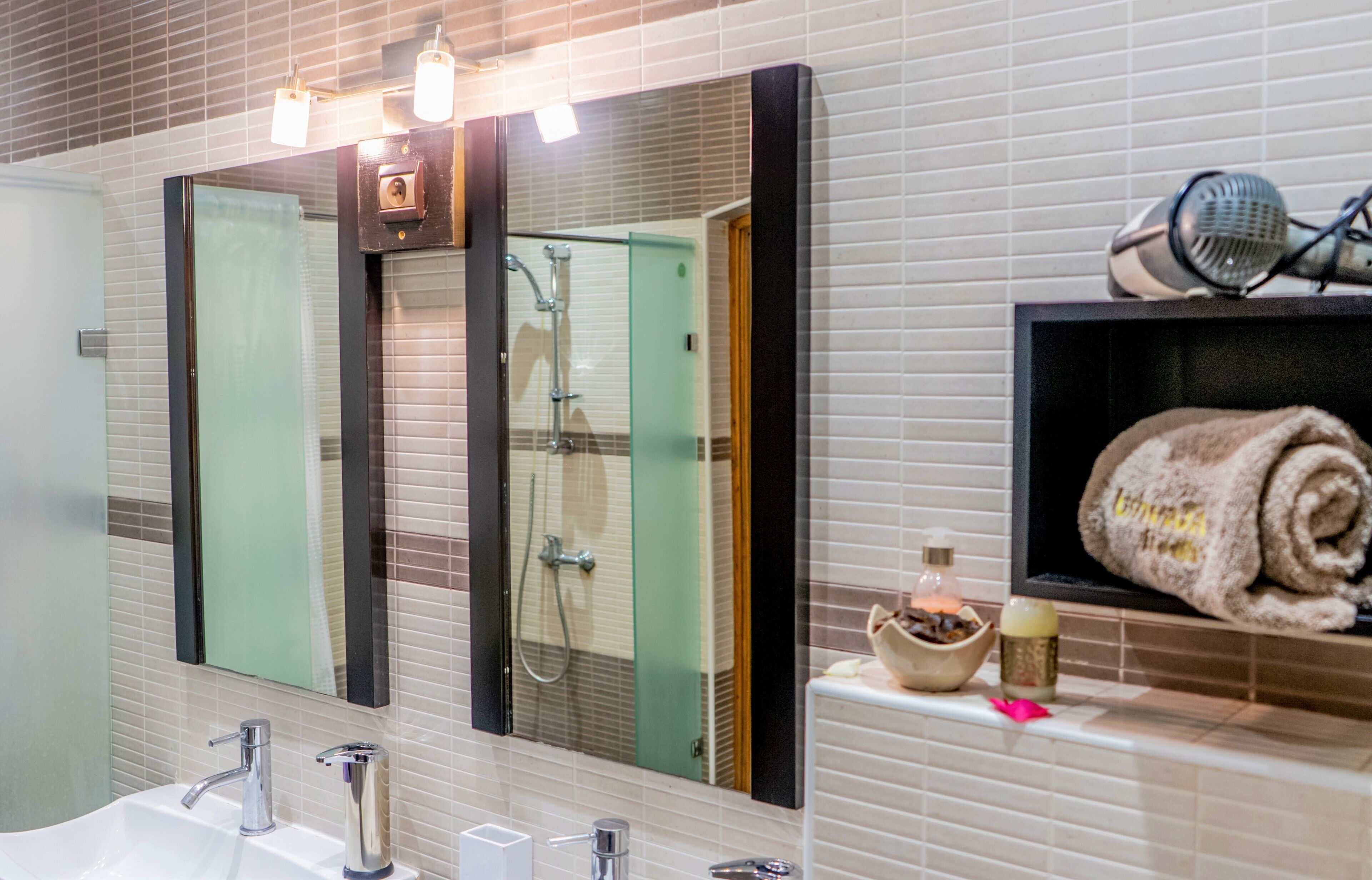 Un baño moderno con un espejo grande, dos lavamanos, una ducha y un perchero con una toalla.
