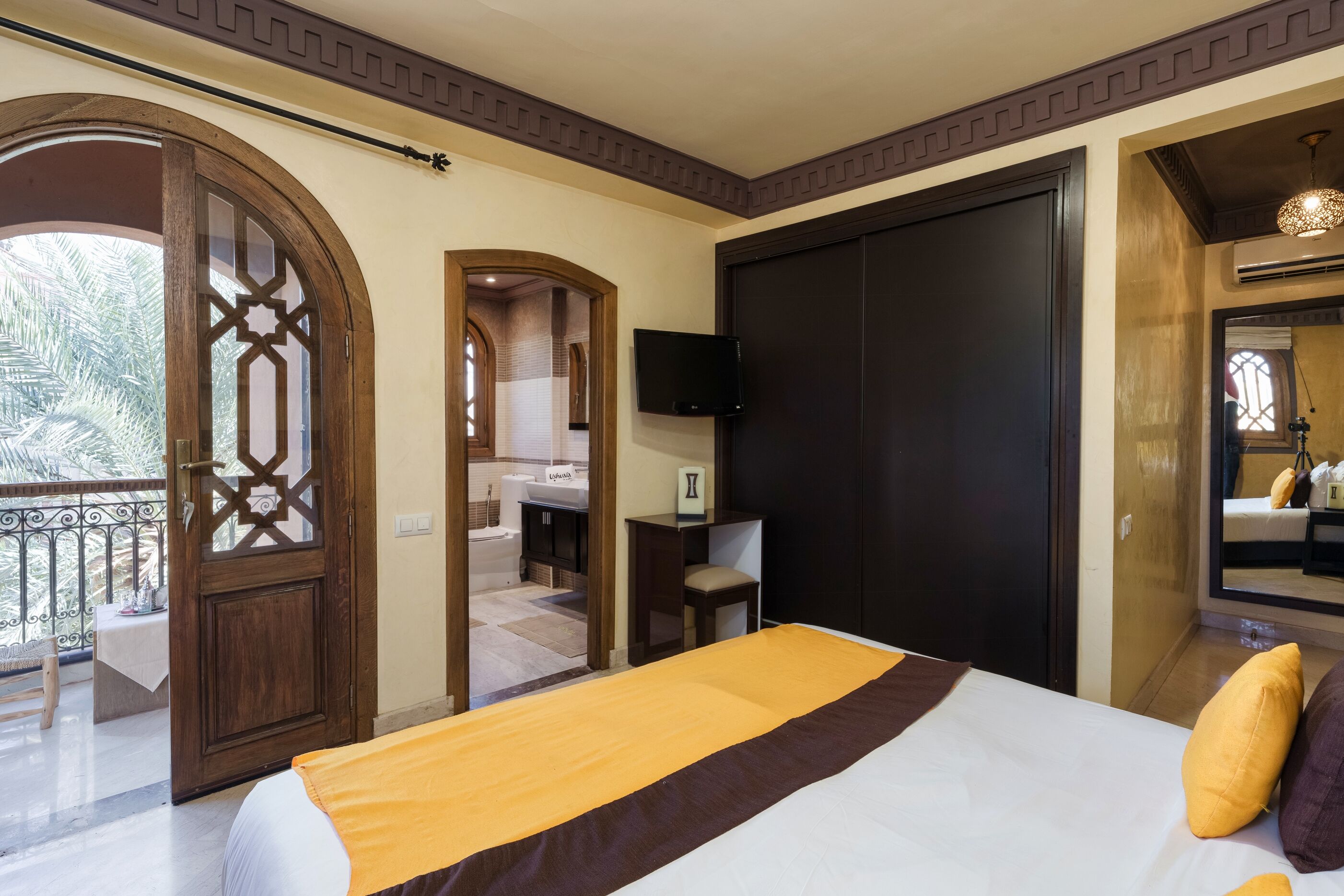 Habitación de hotel con una cama grande, televisión, balcón y vistas a palmeras.