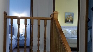 A staircase with wooden balusters leading to a bedroom with a bed and a painting on the wall. - Chambres d'hôtes Elisa & Etienne (Manosque)