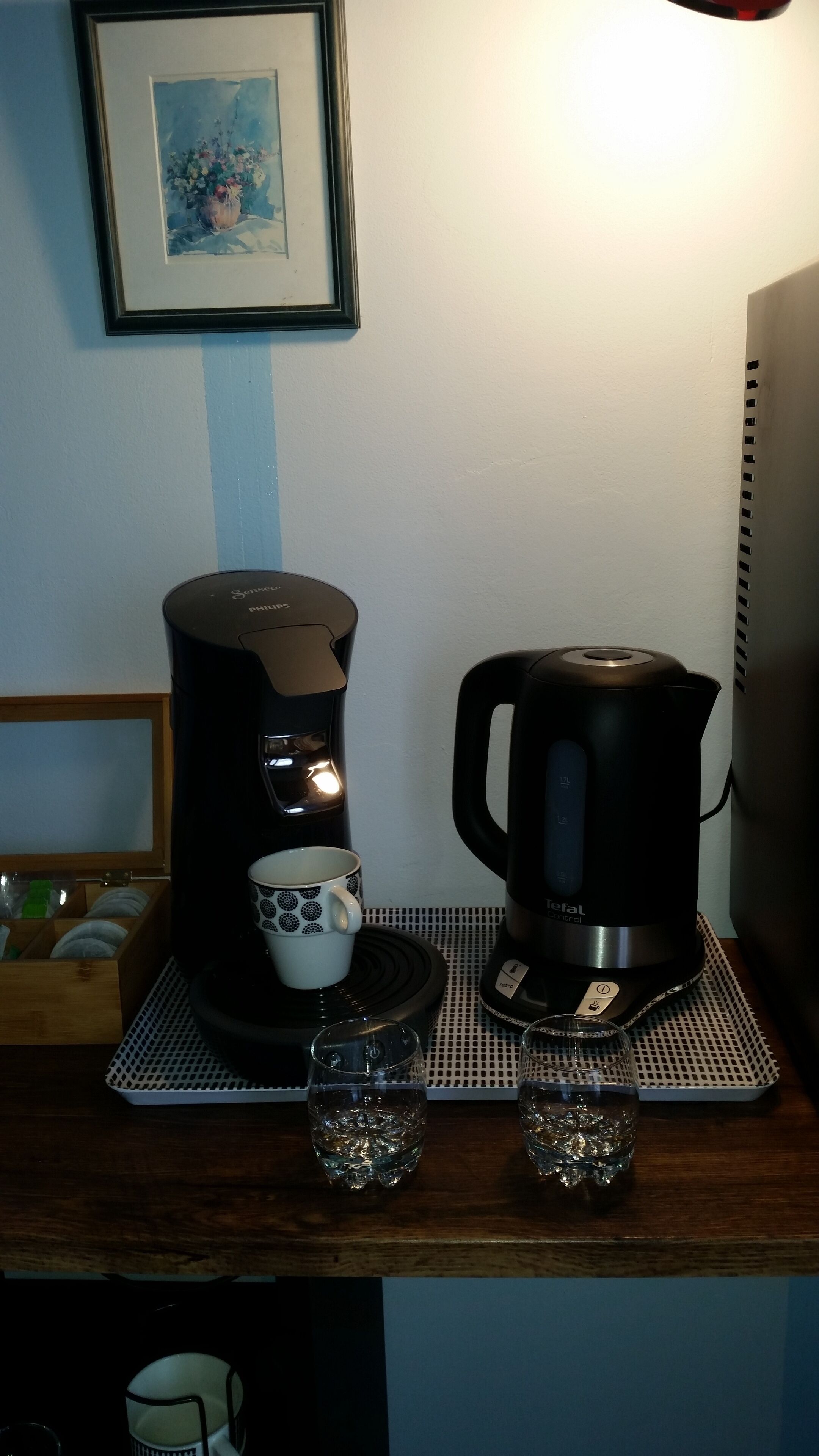 A coffee maker, a teapot, two glasses, and a cup on a wooden surface.