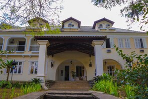 A two-story building with a central entrance, arched doorways, and a covered porch.