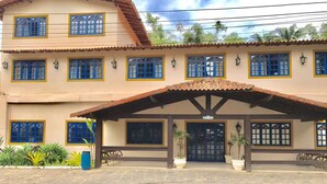 Un edificio de dos pisos con techo de tejas y ventanas con marcos azules.