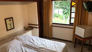 Um quarto com cama, uma escrivaninha pequena, janela com cortinas e um quadro na parede.