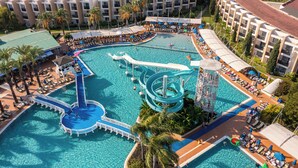 A resort with a large pool, a water slide, and multiple lounge areas.