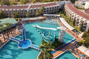 A resort with a large pool, a water slide, and multiple lounge areas.