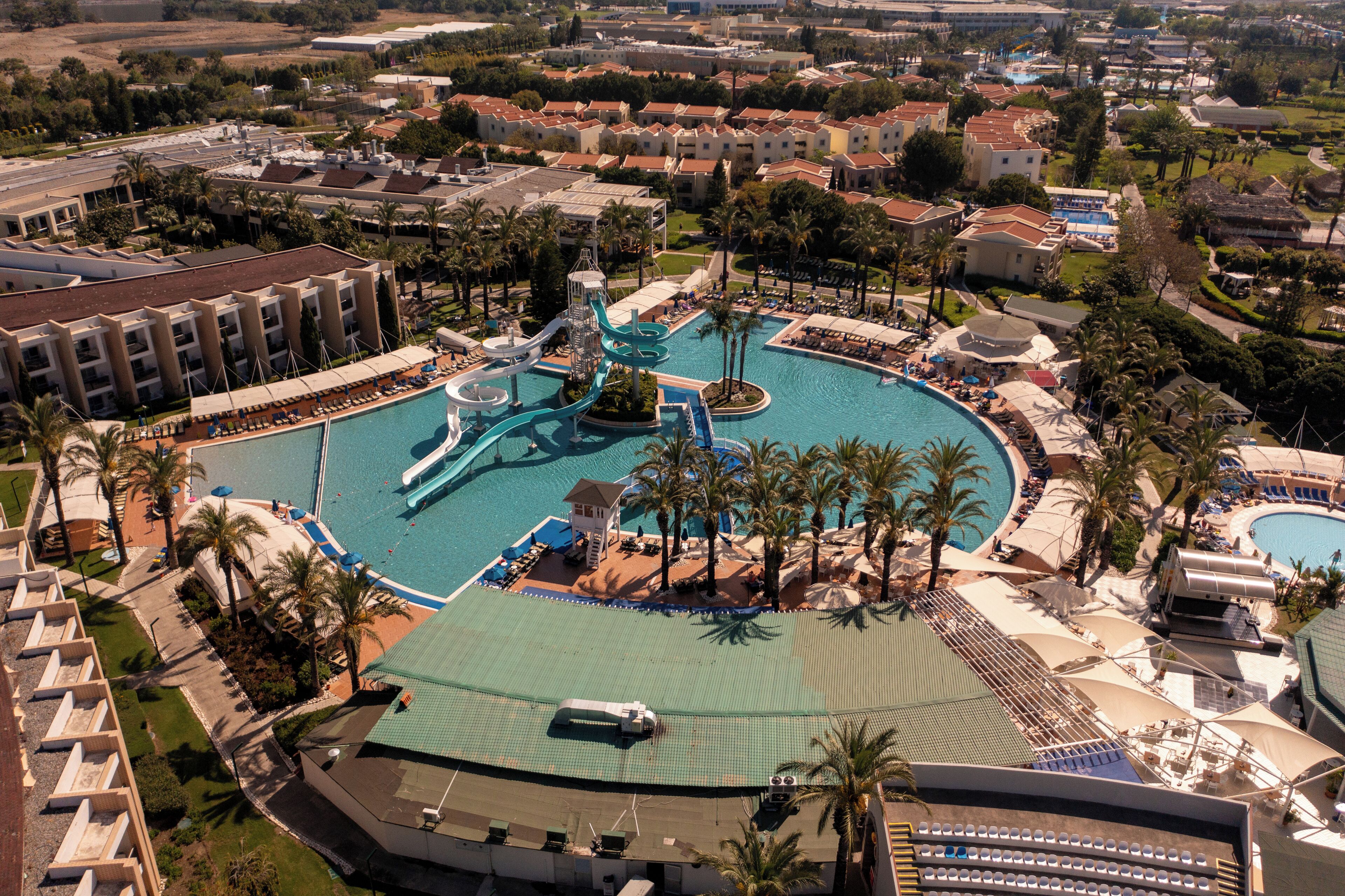 An aerial view of a resort with a large central pool, multiple smaller pools, and a water park.