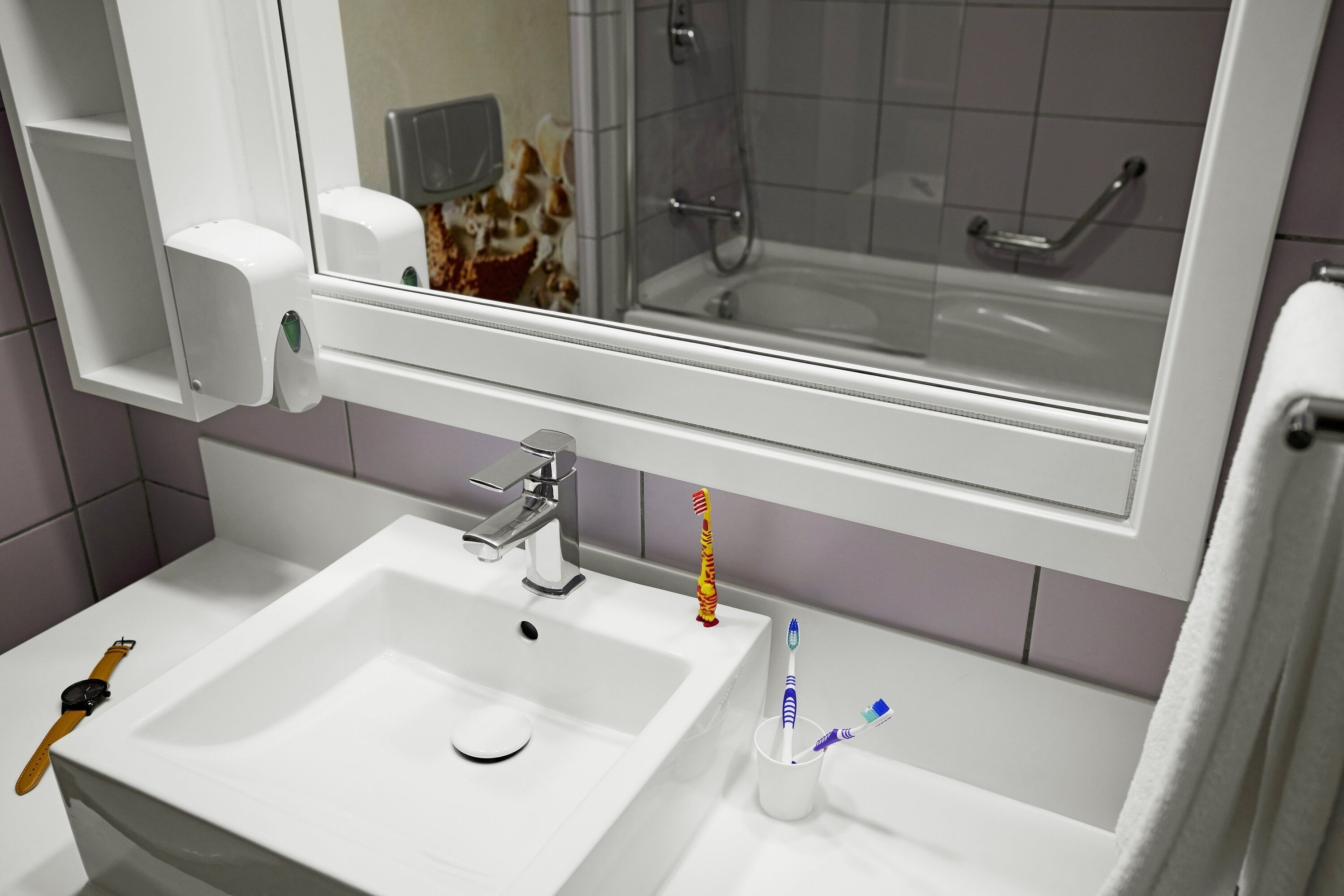 A bathroom with a white sink, a mirror, and a shower visible in the background.