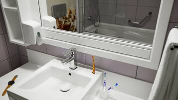 A bathroom with a white sink, a mirror, and a shower visible in the background.