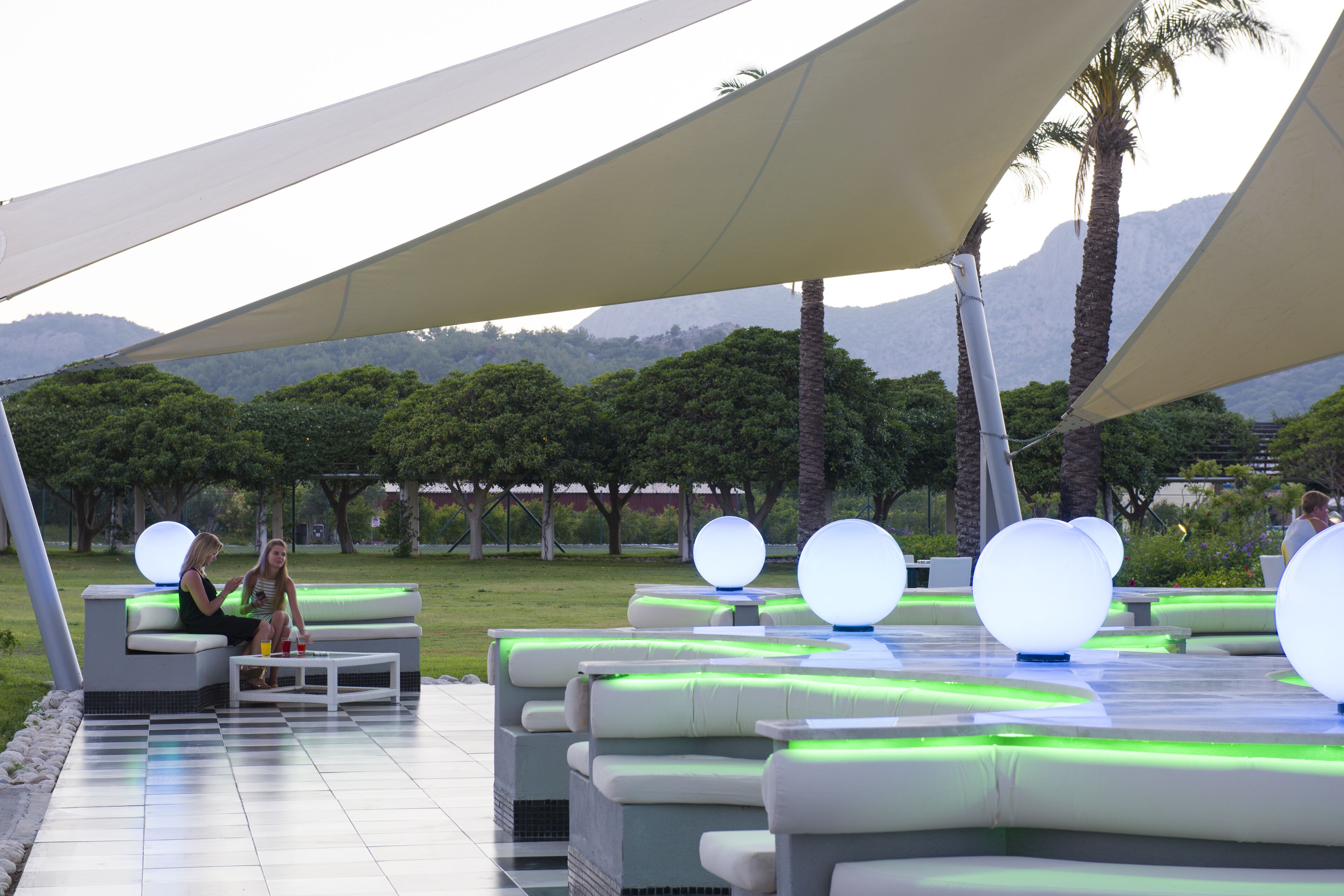 Un espacio exterior con mobiliario moderno e iluminación esférica.