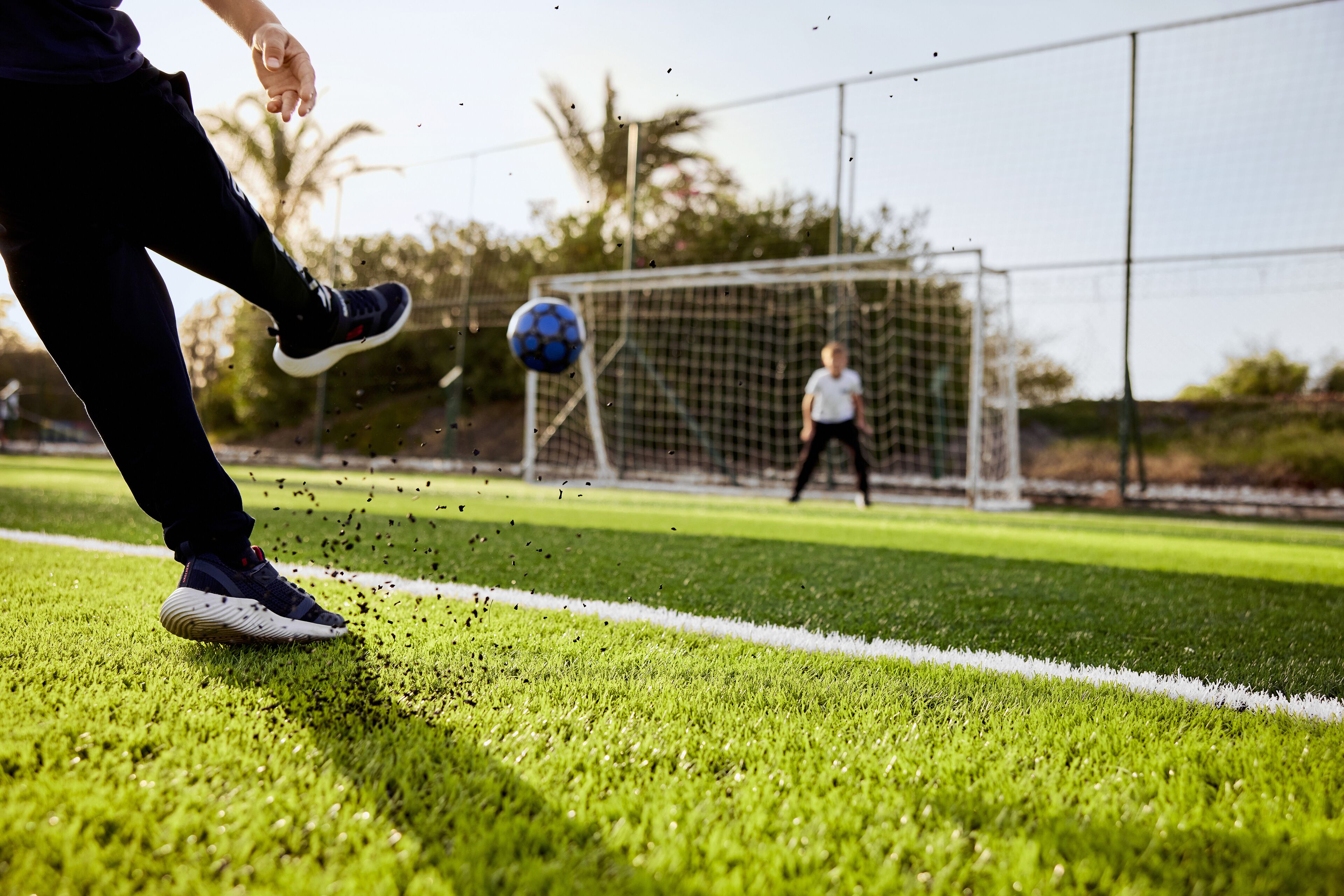 A soccer field with a goalpost and a player in motion.