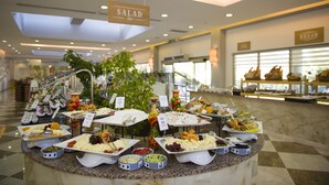 Un bufé con diversas opciones de comida, incluyendo ensaladas, pan y otros platos, dispuesto sobre una barra de mármol en un espacio interior bien iluminado.