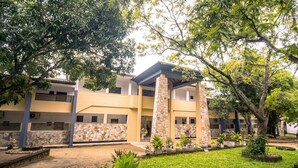 A building with a stone facade, multiple windows, and a covered outdoor area with potted plants. - Lavendish Wild Safari Resort (Maraka)