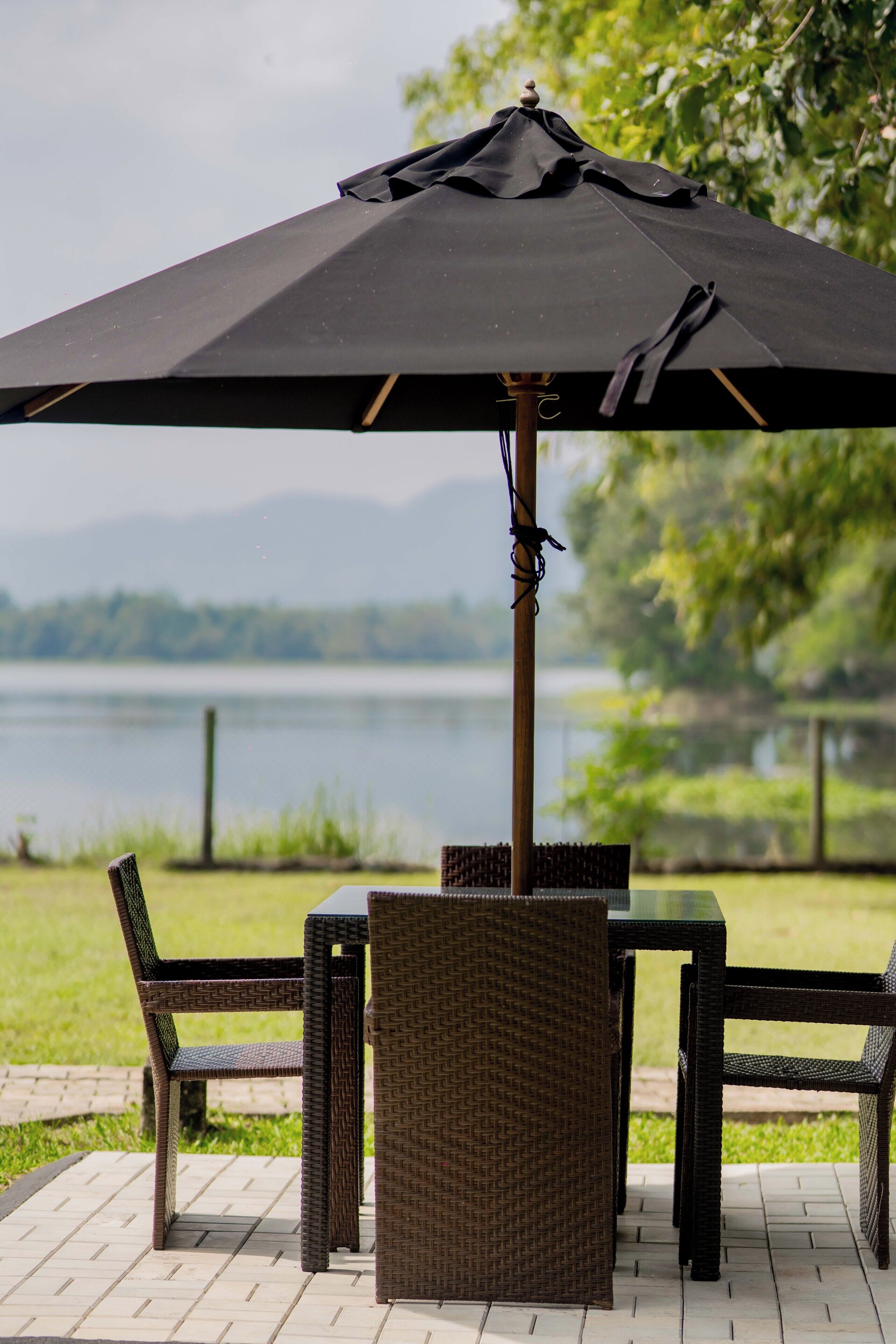 Un patio al aire libre con una mesa, sillas, un paraguas y vistas a un lago.