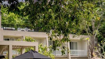 Une cour avec des espaces de repos en plein air, des parasols et un bâtiment doté de balcons.
