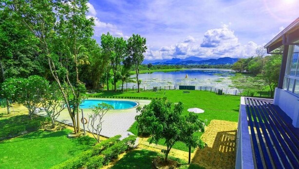 A pool surrounded by lush greenery and a view of a lake and mountains. - Lavendish Wild Safari Resort (Maraka)