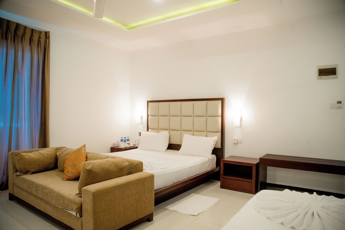 Een hotelkamer met een bed, een bank, een nachtkastje en een bijzettafeltje.