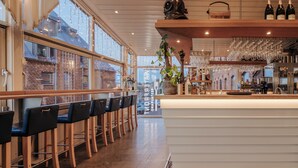 A bar area with wooden chairs, a counter with wine bottles, and hanging glasses. - Quality Hotel Waterfront, Goteborg (Gothenburg)