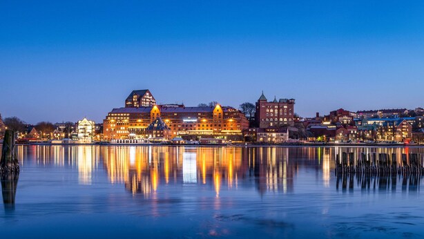 A waterfront cityscape with illuminated buildings reflecting on calm water. - Quality Hotel Waterfront, Goteborg (Gothenburg)